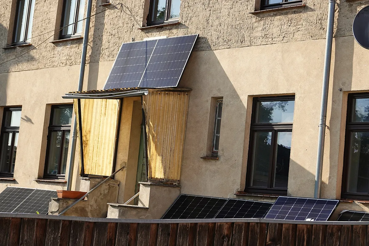 Altbau mit Solarmodulen an Balkon und Zaun