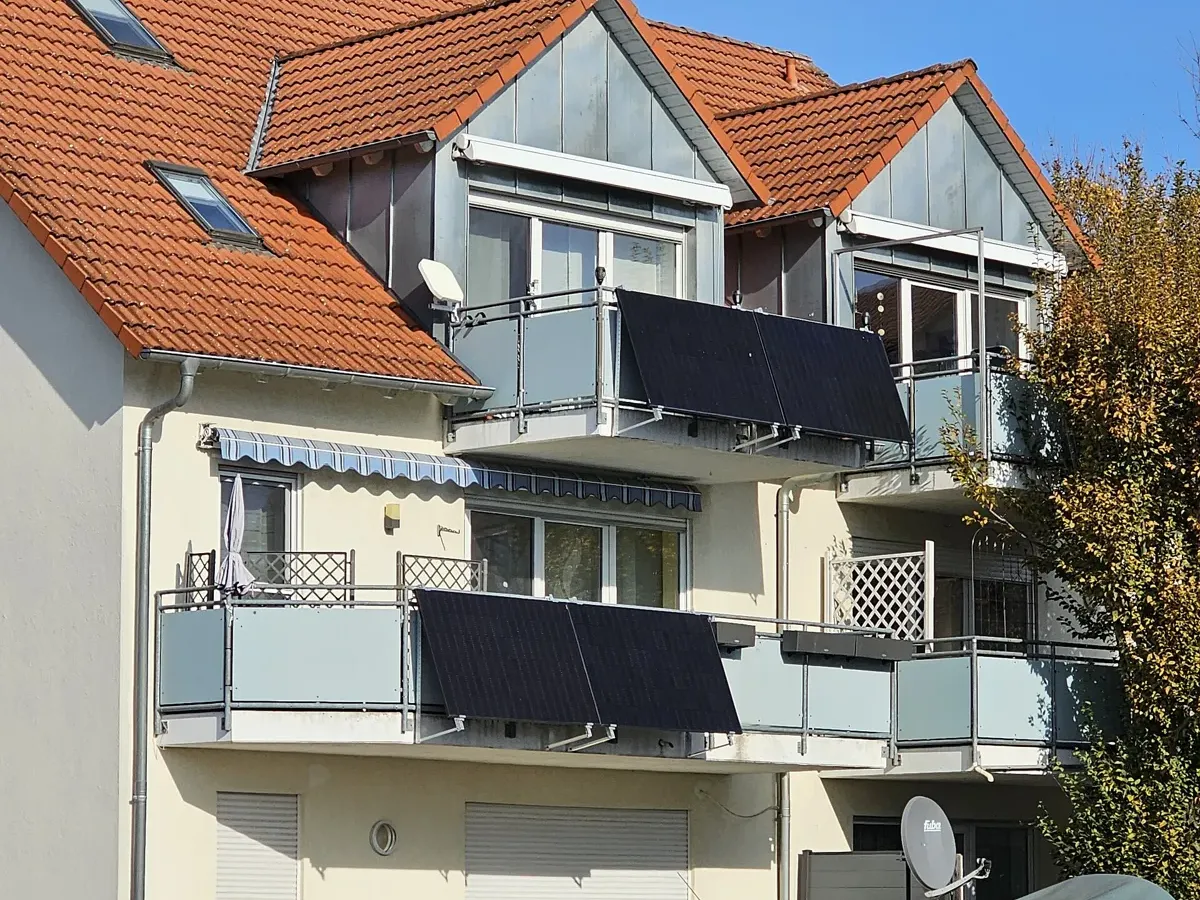 Mehrfamilienhaus mit Solarmodulen an mehreren Balkongeländern